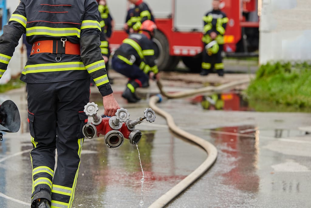 Firefighters in protective gear connecting hoses and equipment during an emergency response.