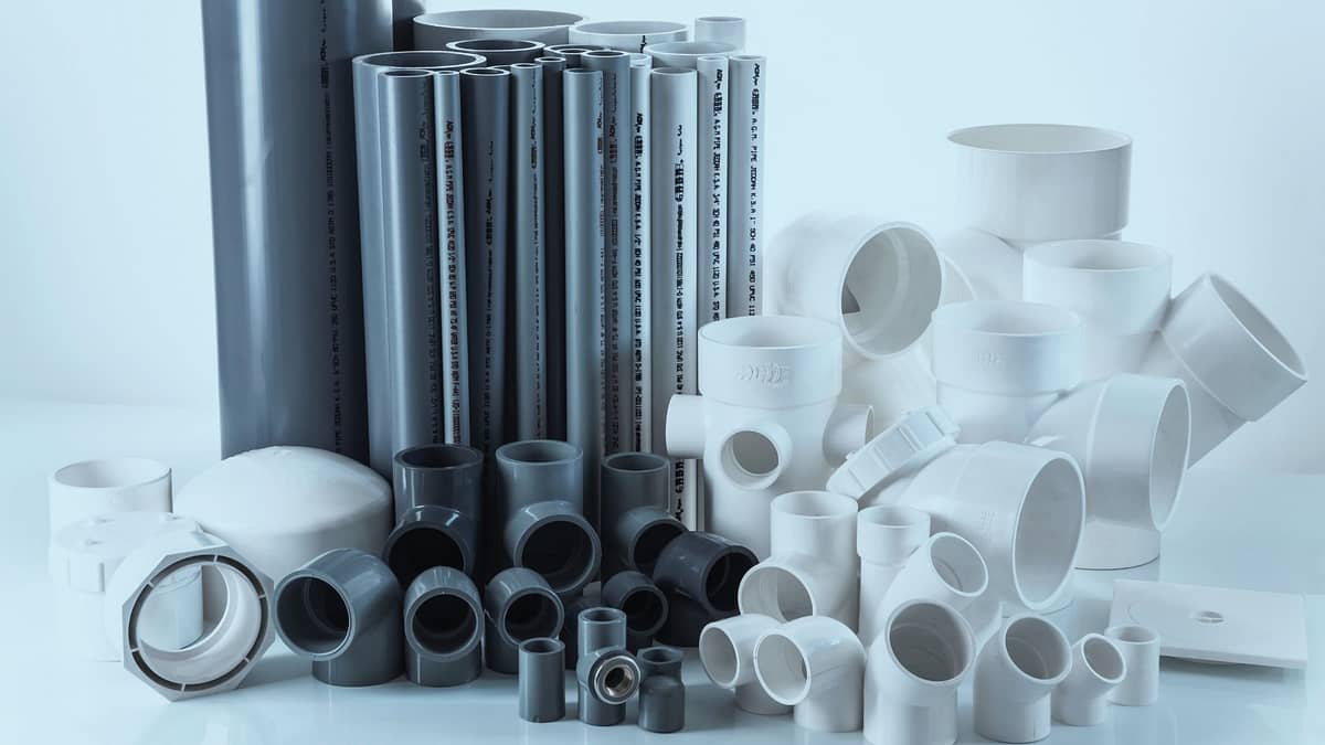 Image of various CPVC pipes and fittings, including gray and white pipes, elbows, and connectors, arranged on a surface, showcasing plumbing components.