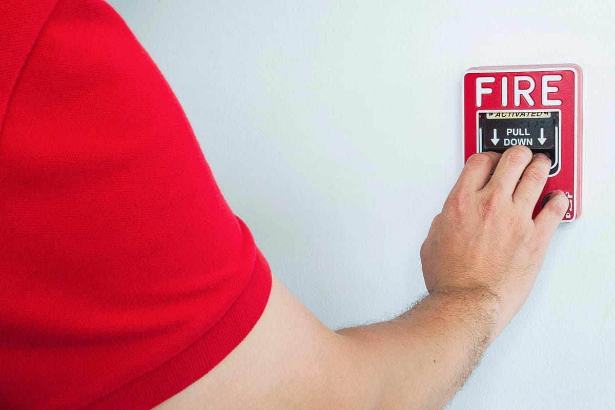 Man reaching out to press a red fire alarm on a wall-mounted hand station. Understanding when a green fire hydrant is used is valuable for maximum efficiency.