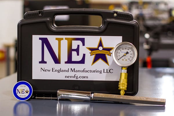 A New England Manufacturing LLC toolkit with a pressure gauge and other accessories.